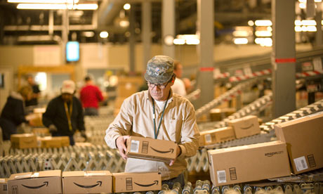 An Amazon employee grabs boxes off the conveyor belt